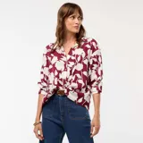 Blusa de corte fluido y holgado con estampado floral en tonos bordó y crema. Presenta cuello camisero, cierre frontal con botones y mangas largas con puños rectos.