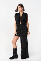 Vestido corto negro con escote profundo en V, diseño sin mangas y detalle de drapeado frontal que se extiende en una caída lateral asimétrica.