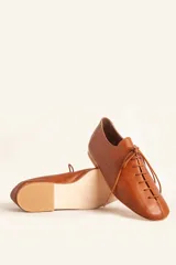 Zapato tipo oxford plano de cuero vacuno en color azul marino, con cordones al tono y suela de cuero.