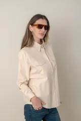 Camisa color crema de manga larga con dos bolsillos frontales con solapa.