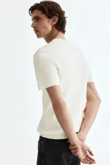 Remera blanca de punto acanalado fino, de corte ajustado, con cuello redondo y mangas cortas.