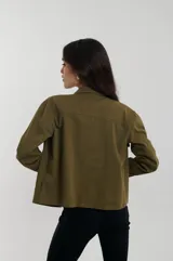Campera de estilo utility con cuello camisero, cierre frontal de botones dorados y bolsillos de parche con solapa en el pecho.