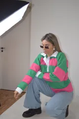 Sweater a rayas horizontales rosas y verdes, con cuello polo blanco y puños blancos.