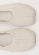 Zapato chatita de cuero ovino color beige, de diseño minimalista con punta redonda y suela de cuero.