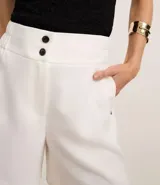 Bermuda roja de poliéster con cintura elástica, bolsillos laterales y cierre con cremallera y botones.