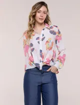 Camisa de gasa blanca con estampado floral multicolor, cuello con solapa, mangas largas y cierre frontal con botones. Cuenta con terminación delantera anudada y espalda más larga.