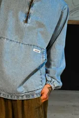 Canguro de denim celeste con capucha, cierre frontal parcial, bolsillo tipo canguro y puños con elástico.
