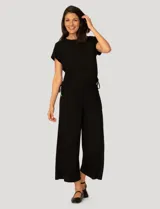 Conjunto de dos piezas compuesto por una remera de manga corta con cuello redondo y frunces laterales ajustables, y un pantalón de corte ancho con cintura elástica y bolsillos laterales.