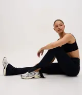 Pantalón deportivo tipo legging flare de tiro alto, confeccionado en microfibra con abertura lateral en el bajo. Presenta un diseño ajustado en la parte superior con caída acampanada hacia el tobillo.