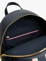 Mochila urbana de diseño estructurado en color azul marino, con franjas verticales en blanco y rojo en el centro. Presenta el logo monograma TH metalizado en la parte superior, bolsillo frontal con cierre y herrajes dorados.