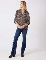 Blusa de gasa estampada con patrón geométrico en tonos azul, marrón y amarillo. Cuello a la base con detalle plisado y escote en V. Manga larga con presilla y botón para regular el largo.