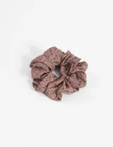 Gomita tipo scrunchie de tela color marrón con estampado de pequeñas manchas negras.