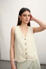 Chaleco sin mangas de corte recto y escote en V, con cierre frontal de botones en contraste. Presenta un diseño minimalista y estructurado.