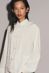 Camisa ZARA Woman Collection de hilatura con mezcla de viscosa, diseño de rayas a contraste, cuello mao y manga larga. Cuenta con bolsillos frontales aplicados y cierre frontal con alamares.