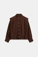 Camisa de corte recto confeccionada en tejido con lino, color marrón. Presenta cuello solapa, manga larga con puños abotonados y detalle de hombreras marcadas. Cierre frontal mediante botones.