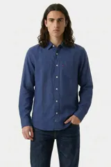 Camisa de manga larga confeccionada en lino, color azul índigo. Presenta cuello clásico, cierre frontal con botones y un bolsillo en el pecho con la etiqueta roja característica de la marca.