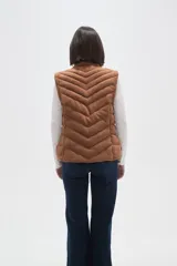 Chaleco acolchado de diseño capitoneado con cierre frontal y bolsillos laterales. Presenta un cuello alto y detalles de botones metálicos decorativos.