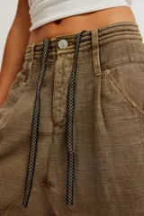 Short de algodón texturado color verde militar, de largo hasta la rodilla y tiro caído estilo harem, con cintura elastizada ajustable mediante cordón, cuatro bolsillos y terminación de ruedo deshilachado.