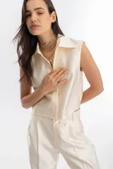 Top sin mangas color crema, de tela taffeta, con cuello clásico y cartera de botones oculta.
