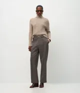 Pantalón de corte recto y entallado con estampado de cuadros escoceses. Presenta cintura estructurada con un aplique metálico decorativo en el centro y costuras verticales frontales que estilizan la silueta.