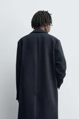 Abrigo de corte regular fit confeccionado en tejido compacto con mezcla de lana. Presenta cuello con solapas de muesca, cierre frontal de botonadura, bolsillos de vivo en la cadera y abertura central en la espalda.