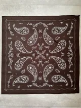 Pañuelo cuadrado de tela con diseño estampado de estilo paisley en color blanco sobre fondo negro.