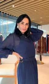 Vestido midi de color azul marino, con mangas largas ligeramente abullonadas y falda plisada. Presenta un diseño con cintura definida y un detalle de hebilla lateral.