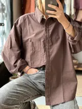 Camisa oversize color marrón con diseño a rayas finas, cuello camisero, manga larga y bolsillo aplicado en el pecho.