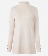 Suéter de punto color crema, con cuello alto, mangas largas y botones decorativos en los puños.