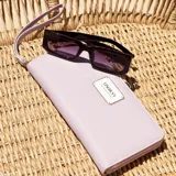 Billetera larga con cierre perimetral, confeccionada en material sintético texturizado color mostaza. Cuenta con correa de mano extraíble y placa metálica con logo de la marca en el frente.