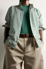 Camisa relaxed fit confeccionada en tejido de algodón, con diseño de rayas verticales en tonos azul y blanco, cuello con botones y manga larga.
