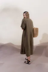 Vestido largo azul oscuro de lino 100% con escote en V, mangas abullonadas con elástico en el puño y pespunte en contraste. Presenta detalle de punto smock en el canesú y bolsillos laterales.