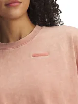 Remera Under Armour de corte cropped y diseño holgado, confeccionada en tejido de mezcla de algodón con efecto lavado. Presenta cuello redondo acanalado y mangas cortas con caída relajada.