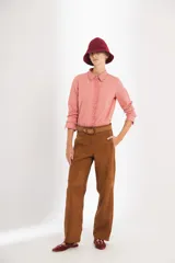 Pantalón de gamuza color marrón, de tiro medio y corte slouchy. Presenta bolsillos laterales y traseros, cierre metálico frontal y forro interno con stretch.