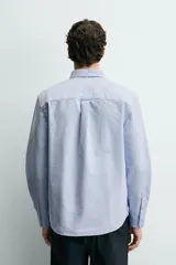 Camisa de corte regular fit confeccionada en tejido de algodón tipo Oxford. Presenta cuello abotonado, manga larga con puños abotonados, bolsillo frontal en el pecho y cierre de botonadura central.
