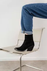 Bota corta de cuero vacuno color negro, con puntera metálica plateada, caña baja, cierre lateral y taco de 7cm. Fabricada en Uruguay.