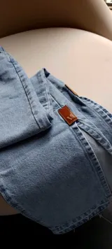 Pantalón de jean celeste de corte recto, con bolsillos delanteros y traseros, y etiqueta de cuero marrón en la parte posterior de la cintura.