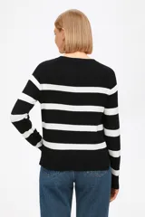 Sweater de punto con diseño de rayas horizontales en azul marino sobre fondo blanco, de corte holgado, cuello redondo y mangas largas con puños acanalados.