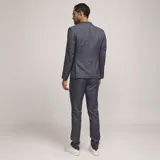 Traje de tres piezas color gris con patrón de cuadros, compuesto por saco con solapas de muesca, chaleco abotonado y pantalón de vestir de corte recto.