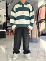 Buzo polo de rayas horizontales en gris oscuro y blanco, con cuello camisero, cierre frontal parcial y corte oversize. Presenta un gran número 88 estampado en la espalda en color bordó junto con la inscripción VCP/ARG.