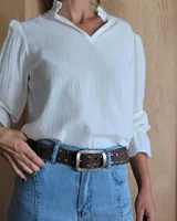 Cinturón de cuero marrón oscuro con tachas metálicas redondas en tonos bronce, plata y dorado. Hebilla rectangular de metal con acabado envejecido.