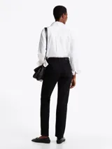 Pantalón de jean negro de corte recto y tiro medio, con cierre de cremallera y botón, cinco bolsillos, y cinturón de cuero negro con hebilla plateada.