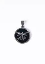Dije circular de acero quirúrgico con diseño de libélula en relieve sobre fondo esmaltado negro.