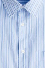 Camisa celeste y blanca a rayas verticales, de corte holgado, manga larga, cuello inglés, bolsillo en el pecho y cierre con botones.