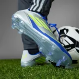 Championes de fútbol Adidas modelo F50 League FG edición Messi, con diseño en tonos plateado, azul y detalles en amarillo neón. Presenta cordones para ajuste, suela con tapones para césped natural y branding de la línea Messi.