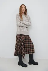 Falda midi de corte irregular con diseño a cuadros en tonos marrones, negros y beige. Presenta una silueta acampanada con caída fluida.