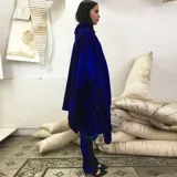 Capa azul de lana merino afieltrada, con guarda tejida en cuello y ruedo. Se puede usar como poncho o como capa abierta.