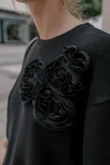Camiseta de cuello redondo y manga corta, con detalle de flores aplicadas en relieve en la parte frontal.