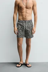 Short de baño largo con estampado geométrico en tonos oscuros sobre fondo claro, cintura elástica ajustable con cordón y bolsillos laterales.