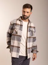 Camisa de franela a cuadros en tonos beige, gris y marrón, con corte regular fit, cuello clásico, cierre de botones frontales y dos bolsillos con solapa en el pecho.